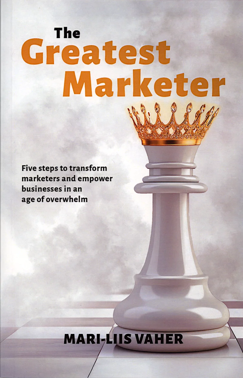 The Greatest Marketer - Mari-Liis Vaher (Powerful Marketers, 2025). Helehalli taustaga kaanel domineerib kuldse krooniga valge malendikuingas, mis sümboliseerib tippjuhti või meistrit. Kujundus on minimalistlik ja elegantne, kasutades tumehalli ja kuldset värvitooni.