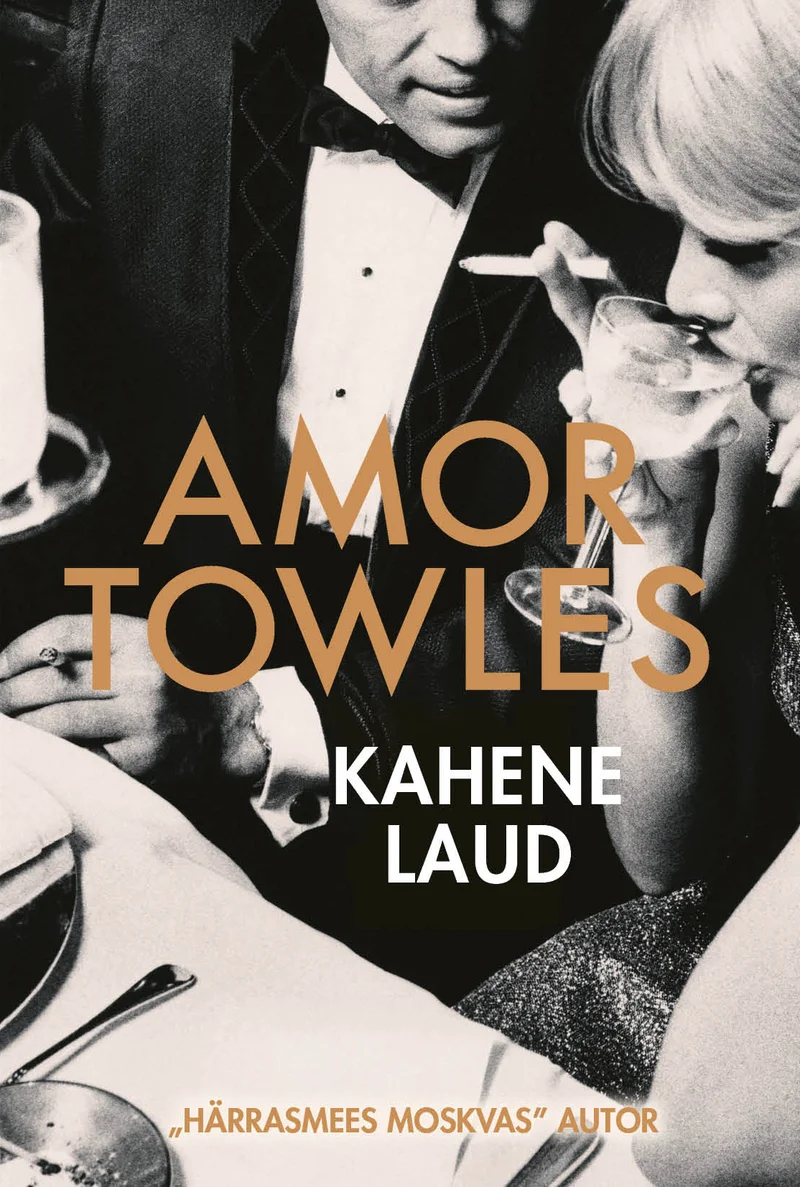 Kahene laud - Amor Towles (Rahva Raamat, 2026). Mustvalge vintage-foto elegantses õhkkonnas, kus kaks inimest istuvad laua taga pidulikus riietuses. Kaane kujundus on lihtne ja klassikaline, kuldse kirjaga pealkirja kontrastiga tumedal taustal.