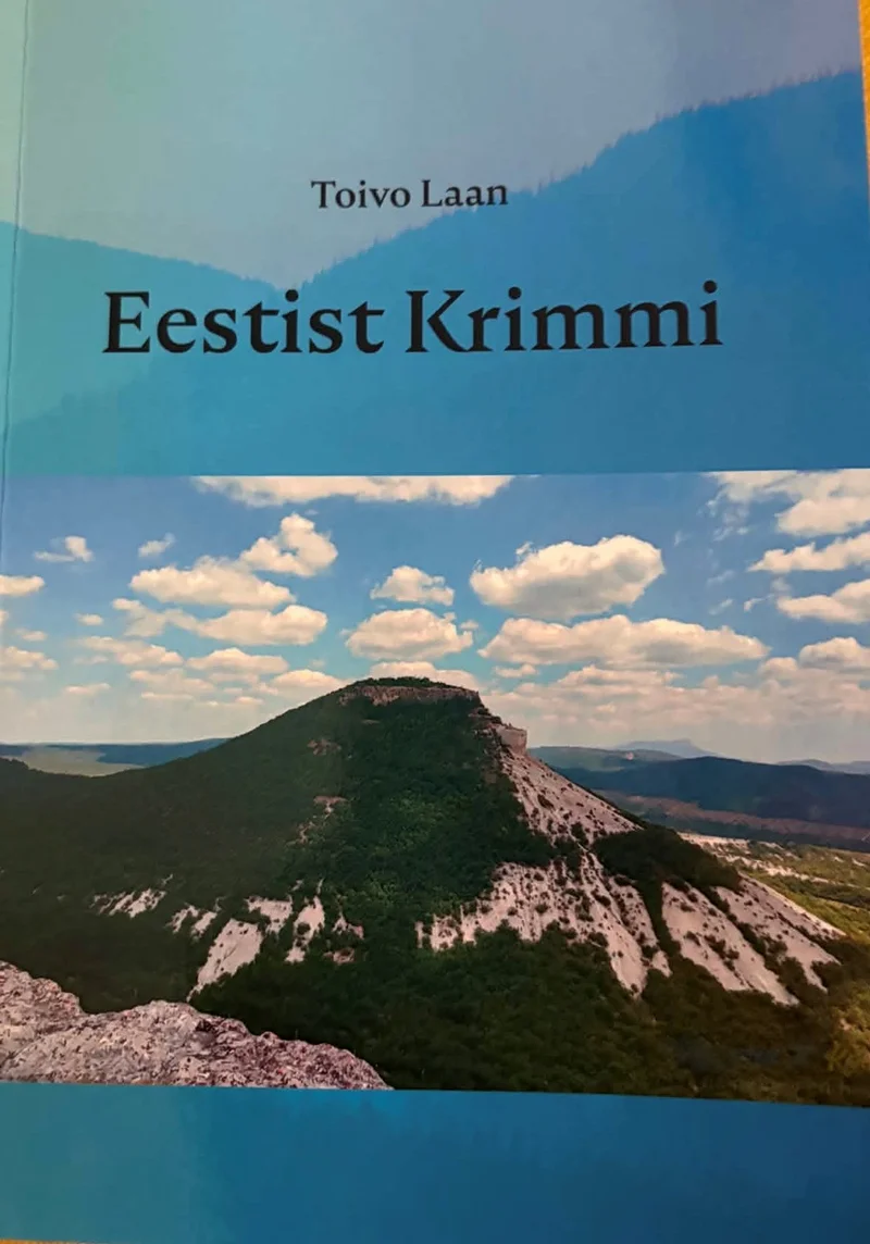 Eestist Krimmi - Toivo Laan (2026). Kaanel domineerib fotorealistlik maastikupilt järsu kaljumäe ja sinise taevaga, millel hõljuvad valged pilved. Ülemine osa on kujundatud helesinist tooni taustal teksti jaoks.